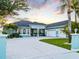 Beautiful property at sunset, featuring a spacious driveway, a lush lawn, and tropical palm trees at 5035 Collingswood Blvd, Port Charlotte, FL 33948