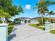 Landscaped property featuring a blue exterior with a large driveway, palm trees and a manicured lawn at 5035 Collingswood Blvd, Port Charlotte, FL 33948