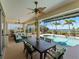 Inviting covered patio featuring a ceiling fan, dining area, and comfortable seating overlooking the pool and scenic water view at 5035 Collingswood Blvd, Port Charlotte, FL 33948