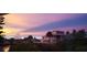 A large waterfront home with multi-story balconies is silhouetted against a colorful sunset sky at 507 Buena Vista Dr, Nokomis, FL 34275