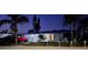 Well-lit home exterior at dusk with tropical landscaping, driveway, and boat parked nearby at 507 Buena Vista Dr, Nokomis, FL 34275