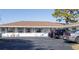 Cottage exterior with parking, inviting Adirondack chairs, white facade, and appealing red shutters at 510 Airport E Ave # 2C, Venice, FL 34285