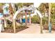 View of the Venice Fishing Pier entrance with palm trees, tropical foliage, and people walking through the archway at 510 Airport E Ave # 2C, Venice, FL 34285