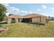 View of spacious backyard with mature tree coverage, stone fire pit, and swing set at 5417 Maccaughey Dr, North Port, FL 34287