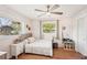 Sun-lit bedroom with ceiling fan, wood floors, and two windows, complemented by a charming dollhouse and decor at 5417 Maccaughey Dr, North Port, FL 34287