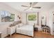 Sun-lit bedroom with ceiling fan, wood floors, and two windows, complemented by a charming dollhouse and decor at 5417 Maccaughey Dr, North Port, FL 34287