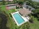 Aerial view of community featuring a large pool, tennis courts, and clubhouse surrounded by mature trees and ponds at 615 May Apple Way, Venice, FL 34293
