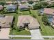 Aerial view of a single-story home with a tile roof, lush landscaping, and a three-car garage in a serene community at 615 May Apple Way, Venice, FL 34293