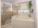 A bright bathroom features a garden tub with a shower and window for added natural light and ventilation at 615 May Apple Way, Venice, FL 34293