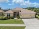 Charming single-story home featuring a beige exterior, tile roof, lush landscaping, and a spacious three-car garage at 615 May Apple Way, Venice, FL 34293
