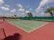 Well-maintained tennis court features a green playing surface and red outer area, with seating along the side at 615 May Apple Way, Venice, FL 34293