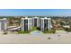 Aerial view of beachfront condos with a swimming pool, green lawns, and white sandy beach at 627 Alhambra Rd # 1103, Venice, FL 34285