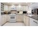Well-lit kitchen featuring white cabinets, granite countertops, and modern appliances at 627 Alhambra Rd # 1103, Venice, FL 34285