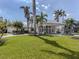 Elegant single-story home with grand entrance, lush lawn, and swaying palm trees at 701 Laguna Dr, Venice, FL 34285
