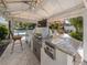 Gourmet outdoor kitchen with stainless steel grill and bar seating overlooking the pool at 701 Laguna Dr, Venice, FL 34285