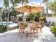 Outdoor patio featuring a dining table, seating for six, and large umbrella near a sparkling pool at 701 Laguna Dr, Venice, FL 34285
