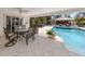 Covered patio with a ceiling fan, dining table, seating, and a view of the pool and lush landscaping at 701 Laguna Dr, Venice, FL 34285