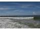Picturesque view of the beach with blue skies, waves, and a pier in the distance at 942 Capri Isles Blvd # 105, Venice, FL 34292