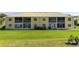 Rear exterior of a yellow condo building with screened patios and a green lawn at 942 Capri Isles Blvd # 105, Venice, FL 34292