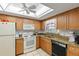 Charming kitchen with bright wooden cabinets, granite countertops, and white appliances at 942 Capri Isles Blvd # 105, Venice, FL 34292