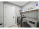 A practical laundry room with modern washer and dryer, shelving for storage, and a door at 10047 Greetings St, Port Charlotte, FL 33981