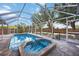 Sparkling screened pool and spa offer a refreshing oasis with ample patio space and serene backyard views at 10047 Greetings St, Port Charlotte, FL 33981
