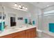 Bathroom with double sinks, wood cabinets, tiled floors, and a glass-enclosed shower at 11007 Batello Dr, Venice, FL 34292
