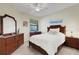 Bedroom featuring a ceiling fan, light wood floors, and dark wood furniture at 11007 Batello Dr, Venice, FL 34292