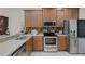 Modern kitchen with stainless steel appliances, wooden cabinets, and stylish tile backsplash at 11007 Batello Dr, Venice, FL 34292