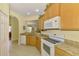 Well-lit kitchen featuring granite counters, white appliances, and ample cabinet space at 11096 Campazzo Dr, Venice, FL 34292