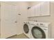 Well-lit laundry room featuring a white washer and dryer set with wall-mounted cabinets at 11096 Campazzo Dr, Venice, FL 34292
