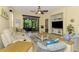 Bright living room features tile floors, neutral paint, ceiling fan, and sliding glass doors to outdoor space at 11096 Campazzo Dr, Venice, FL 34292