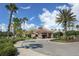 Community clubhouse with a circular drive, tile roof, stone facade and mature palm tree landscaping on a sunny day at 11924 Tempest Harbor Loop, Venice, FL 34292