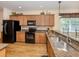 Kitchen featuring granite counters, wooden cabinets, stainless sink and black appliances at 11924 Tempest Harbor Loop, Venice, FL 34292