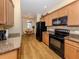 Kitchen featuring granite counters, wooden cabinets, stainless sink and black appliances at 11924 Tempest Harbor Loop, Venice, FL 34292