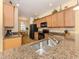 Kitchen featuring granite counters, wooden cabinets, stainless sink and black appliances at 11924 Tempest Harbor Loop, Venice, FL 34292