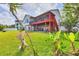 Large backyard featuring a covered patio, wood lawn ornaments, and various tropical plants at 1500 Lemon Bay Dr, Venice, FL 34293