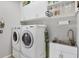 Well-organized laundry room with white cabinetry and modern washer and dryer units at 1500 Lemon Bay Dr, Venice, FL 34293