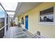 Side view of a screened porch area featuring tile flooring and a bright blue front door at 1537 Overbrook Rd, Englewood, FL 34223