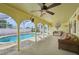 Covered lanai with wicker furniture overlooking a crystal clear swimming pool and tropical landscape at 1537 Overbrook Rd, Englewood, FL 34223