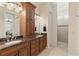Bathroom featuring double sinks with granite countertops, wooden cabinetry, and walk-in shower at 1625 Lancashire Dr, Venice, FL 34293