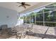 Covered outdoor patio with a seating area, ceiling fan, and serene views of the surrounding greenery at 1625 Lancashire Dr, Venice, FL 34293