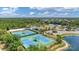 Aerial view showcasing community tennis courts and lush landscaping with pond at 2094 Mesic Hammock Way, Venice, FL 34292