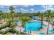 Aerial view of a community pool surrounded by palm trees, lounge chairs, umbrellas, and a play area at 2094 Mesic Hammock Way, Venice, FL 34292