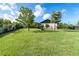 Large green lawn with trees and black fencing enclosing the yard and a glimpse of the home at 23 Tiffany St, Englewood, FL 34223