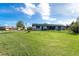 Large green lawn, partial view of the black-fenced home, and American flag in distance at 23 Tiffany St, Englewood, FL 34223