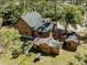 Aerial view of a log cabin with outbuildings, well pump, and lush lawn surrounded by mature trees at 2450 Flagami Ln, North Port, FL 34286