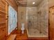 Bathroom features a glass enclosed shower, wood walls, floors, and a window with lace curtains at 2450 Flagami Ln, North Port, FL 34286