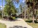 Beautiful log cabin style home with a gravel driveway, mature trees, and attached garage at 2450 Flagami Ln, North Port, FL 34286