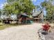 Log home with a stone chimney, green garage doors, a charming porch, and well-maintained landscaping at 2450 Flagami Ln, North Port, FL 34286
